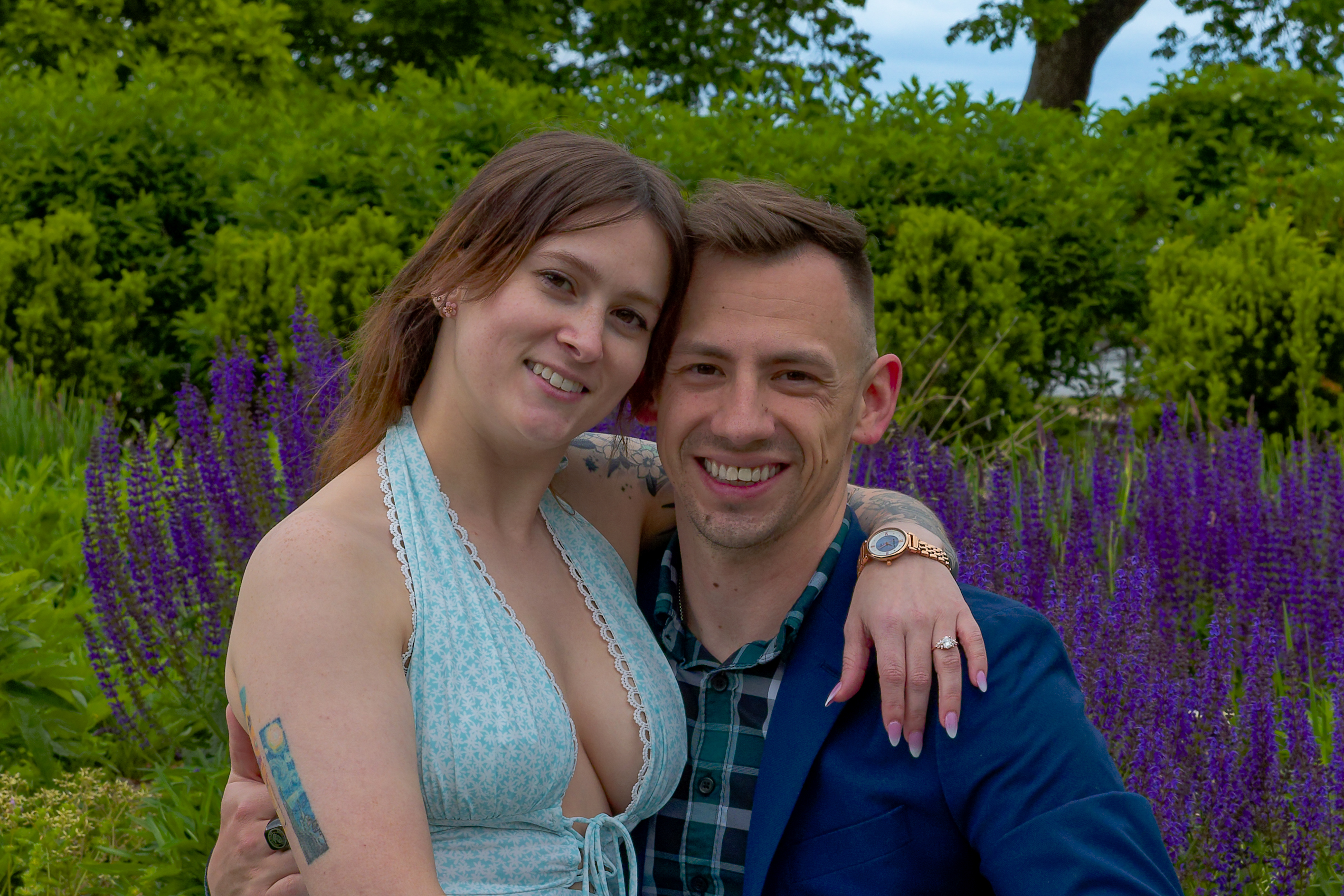 The newly engaged couple smiling together among the salvia